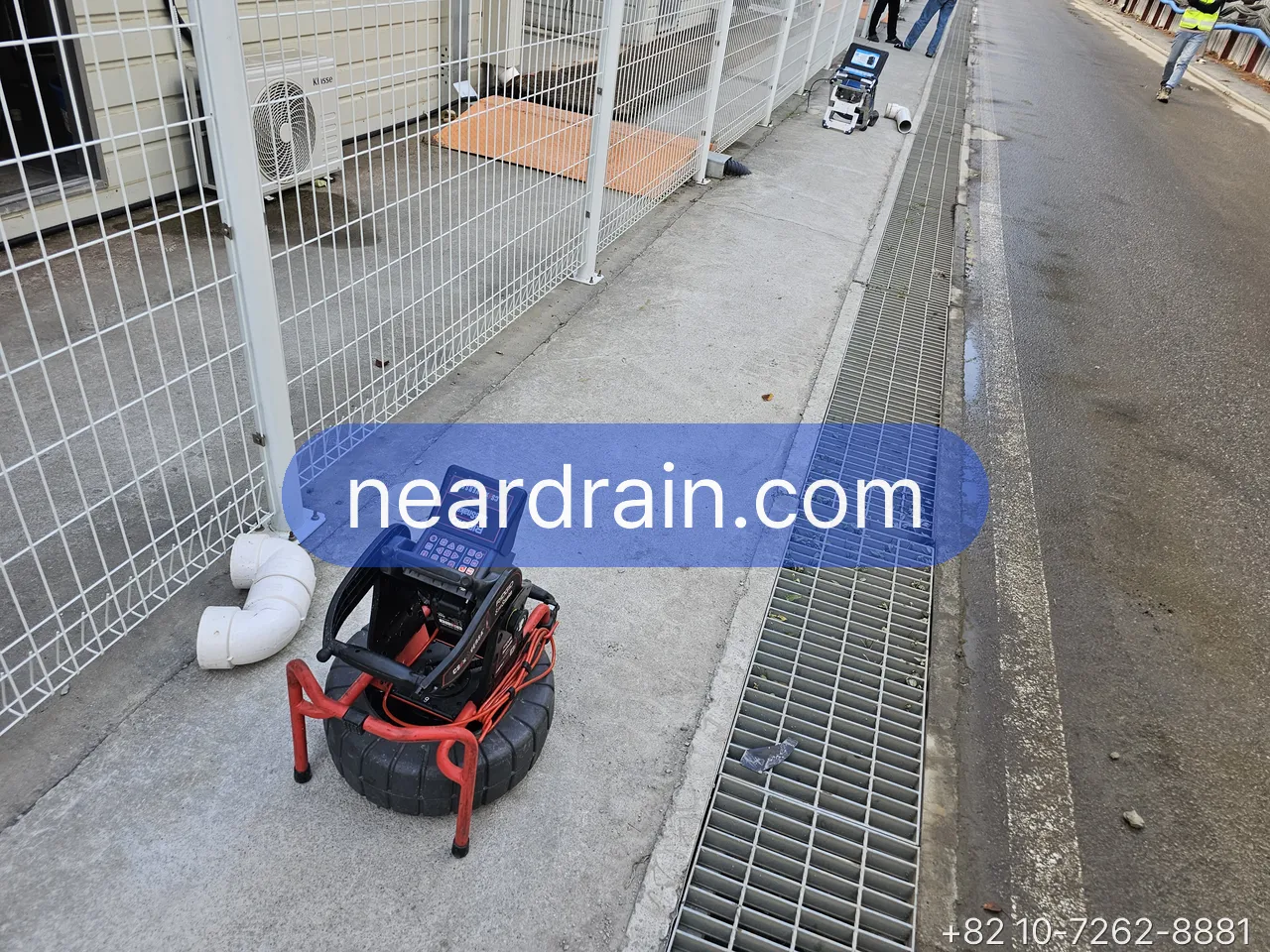 Drain camera reel set beside a trench drain after jetting for the verification pass