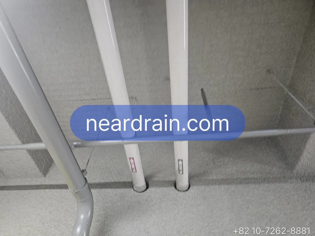 White supply pipes rising through a concrete utility shaft in an apartment building, isolation valves on each branch
