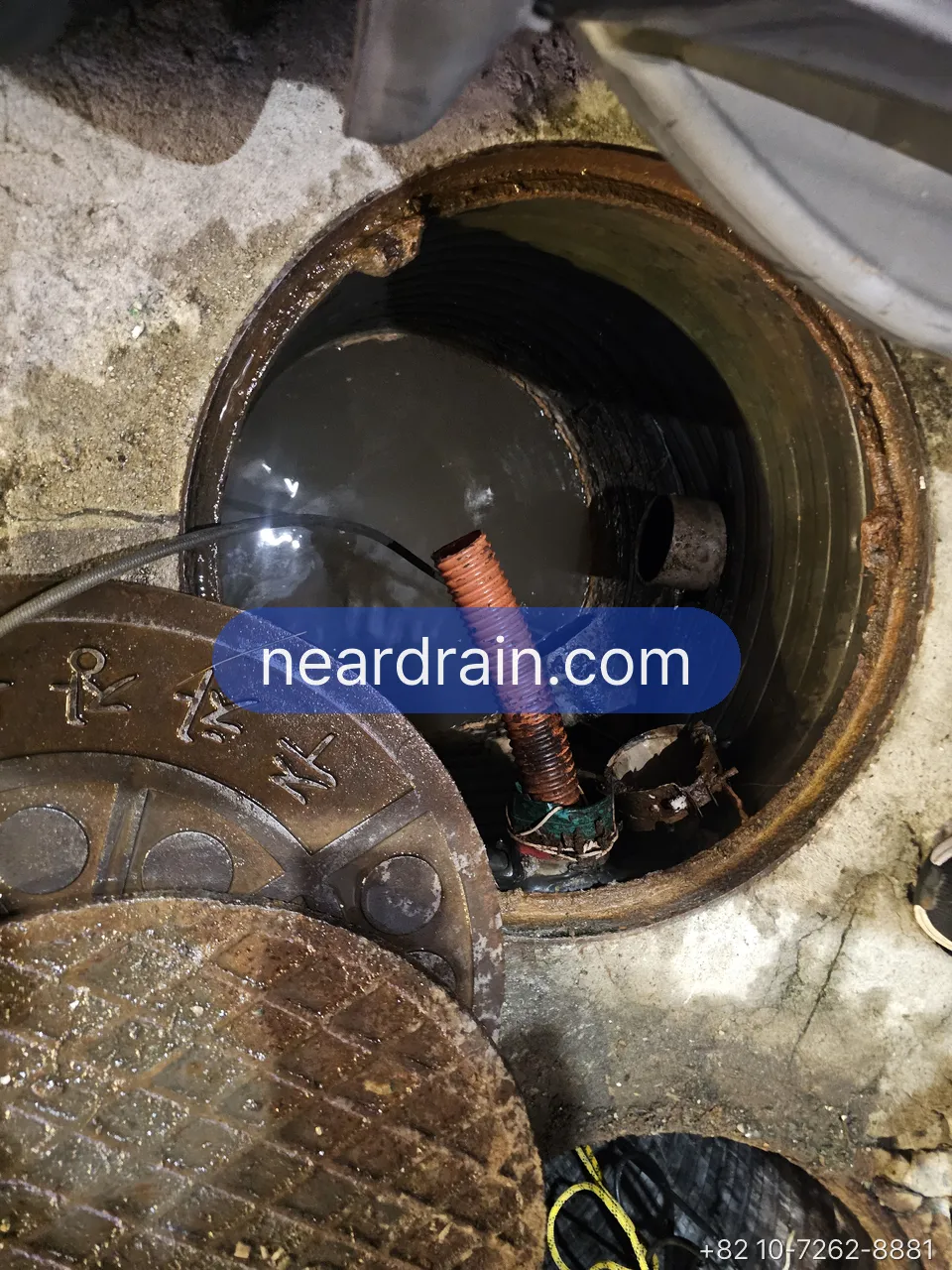 Basement shop sewage pit hatch open at night with discharge hose in place