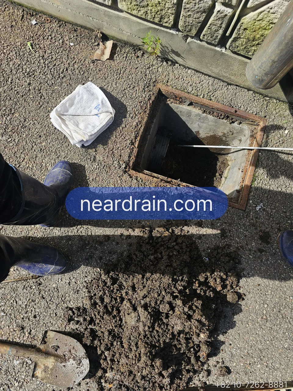 Silt shoveled out of a rain gully onto the pavement beside the open box
