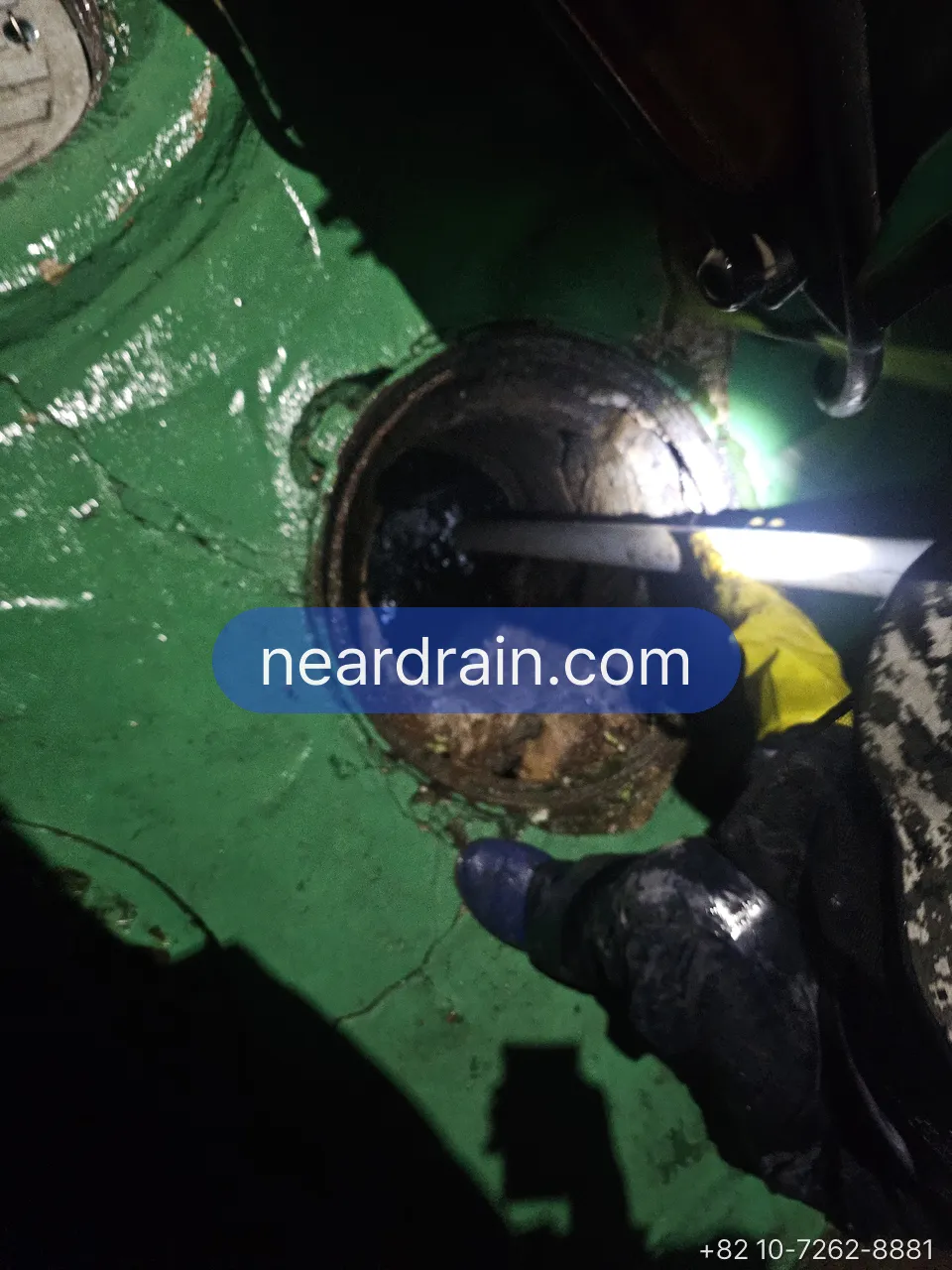 Roof drain on a green waterproofed rooftop opened with a cable being fed into the downpipe
