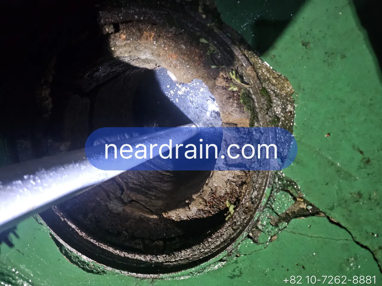Jetting nozzle held at an opened roof drain on a green rooftop membrane
