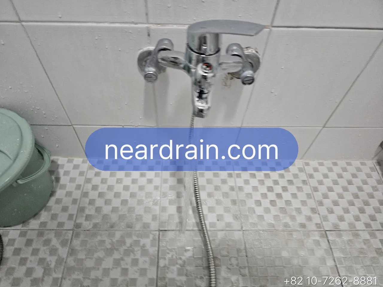 Chrome wall-mounted Korean shower mixer with a single lever on white tile, hand shower hose hanging to the floor